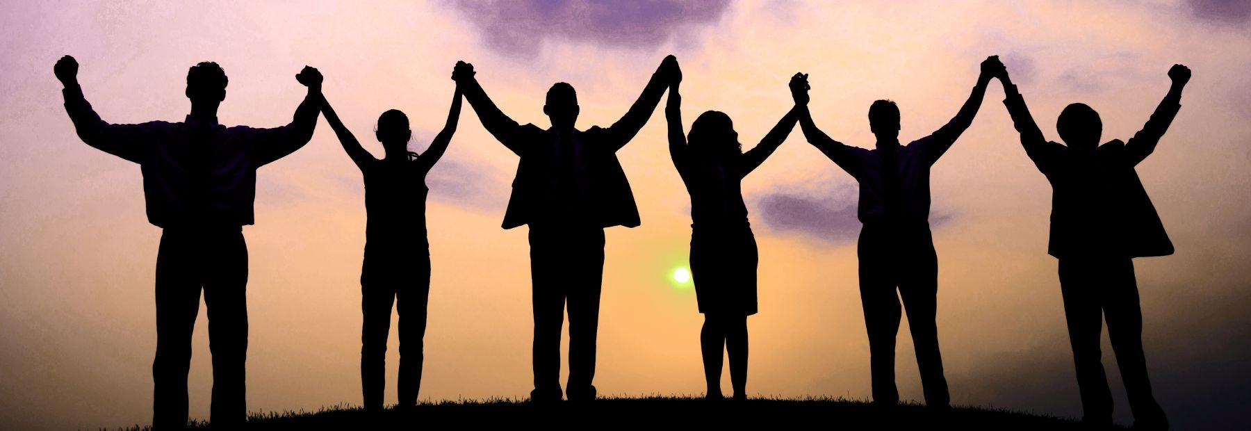 SoulMe Family — gegenseitiges Stärken: sechs Menschen Hand in Hand vor Abendhimmel